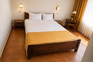 a bedroom with a bed with white sheets and two tables at Tortuga in Costinesti +4 photos