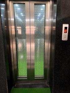 a metal elevator with green floors and glass walls at Bits Pilani Resort in Bagar