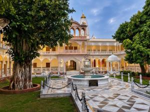 a large building with a fountain and a tree at Bits Pilani Resort in Bagar