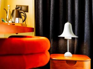 a living room with a chair and a lamp on a table at &Tales Hotel - Óbidos in Óbidos