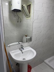 a white bathroom with a sink and a mirror at Studio 3rd Floor Blumar one bedroom in El Alamein +8 photos