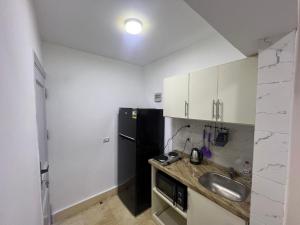 a kitchen with a sink and a black refrigerator at Studio 3rd Floor Blumar one bedroom in El Alamein