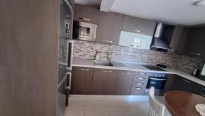 a kitchen with brown cabinets and a sink and microwave at revisapartments brown in Neos Marmaras