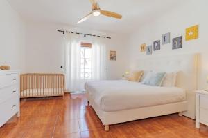 a white bedroom with a bed and a ceiling fan at Baleal Happiness Surf House in Baleal