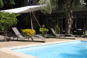 a swimming pool with chairs next to a house at Lariad BnB in Flic-en-Flac
