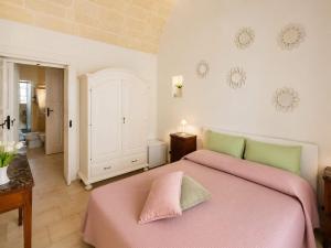 a bedroom with a bed with pink sheets and green pillows at Dimora IL TULIPANO BIANCO in Massafra