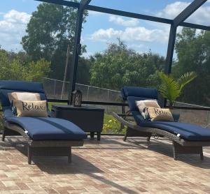 a patio with two blue chairs and a table at Serenity Garden Studio with Pool in Naples