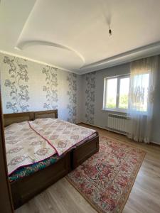 a bedroom with a bed and a rug and a window at Panorama in Karakol