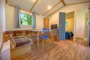 a living room with a couch and a table and chairs at Manoir le Mingreaud Bungalows in Sainte-Gemme-la-Plaine