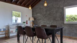 a dining room with a black table and chairs at Villa Capelinhos in Capelo +46 photos