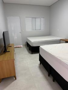 a room with two beds and a desk and a television at Residência Araguaia in Aruanã +9 photos