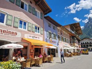 a group of people sitting at tables outside a building at Gästehaus La Puccia in Mittenwald