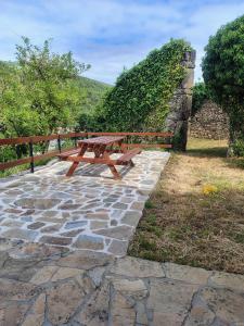 a wooden picnic table sitting on a stone patio at Casa Do Centeal in Arrueiro
