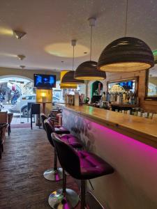 a bar with purple bar stools in a restaurant at Gästehaus La Puccia in Mittenwald