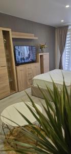 a bedroom with two beds and a flat screen tv at Yellow Apartment Mažeikiai in Mažeikiai