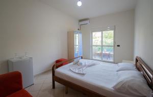 a white bedroom with a bed and a window at Serxhio Apartments in Golem