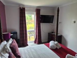 a bedroom with a bed and a tv and a window at Remus B&B in Lochgelly