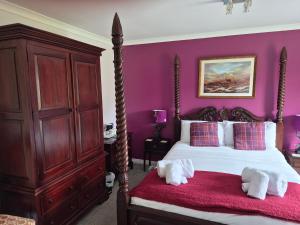 a bedroom with purple walls and a bed with towels at Remus B&B in Lochgelly