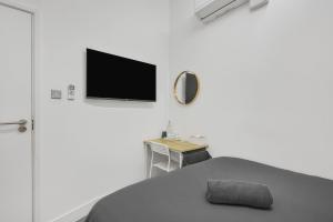 a room with a table and a tv on a wall at Cosy Rooms in London