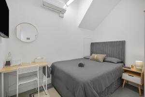 a bedroom with a bed and a desk and a mirror at Cosy Rooms in London
