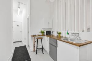 a white kitchen with a sink and a counter at Cosy Rooms in London