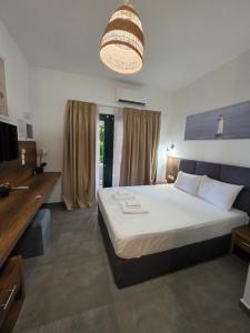 a bedroom with a large white bed and a chandelier at Sophia seaview suites & restaurant in Nea Vrasna