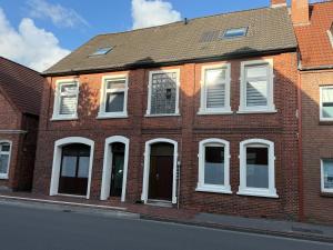 a red brick building with white windows on a street at Logger in Emden
