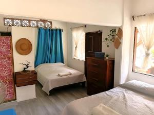 a bedroom with two beds and blue curtains at Casa Tania in Mazunte