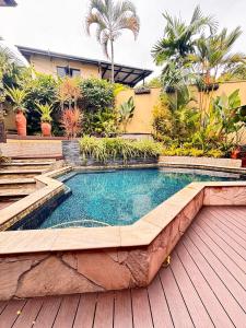 a swimming pool in a backyard with a wooden deck at Serenity Garden Escape in Port-of-Spain