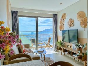 a living room with a couch and a large window at The Song Apartment - Căn Hộ Du Lịch 5 Sao Cạnh Biển Vũng Tàu in Vung Tau