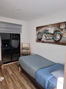 a bedroom with a bed and a painting of a motorcycle on the wall at Tu rinconcito entre cerros in Requínoa