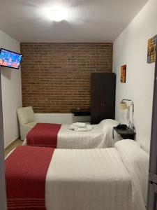 a hotel room with two beds and a chair at Hostería Boulevard in Villa María