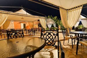 an outdoor patio with tables and chairs and an umbrella at Tenuta Masseria del Gallo in Calimera