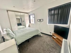 a bedroom with a bed and a flat screen tv at Rest & Recover in Wednesbury