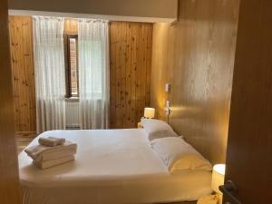 a bedroom with a large bed with white sheets and pillows at Residence Rododendro in Passo San Pellegrino