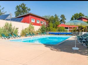 a swimming pool with chairs and an umbrella at Chalet gris 4 in Chaveignes