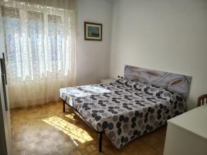 a bedroom with a bed and a window with curtains at la casa rosa in Breguzzo