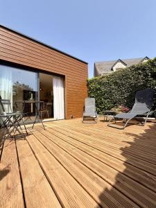 a wooden deck with two chairs and a table at Le Cocon de May entre Terre et Mer a proximité de caen in May-sur-Orne
