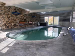 a swimming pool in a room with a stone wall at B&B Les Trois Voisins in Bourseigne-Vieille