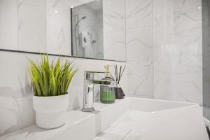 a white bathroom with a sink and a mirror at Cosy Rooms in London