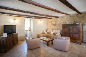 a living room with a couch and chairs and a tv at Le refuge à la campagne in Toulonjac