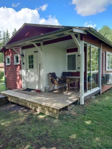 a small house with a porch and a deck at Stuga vad vatten in Åsarp