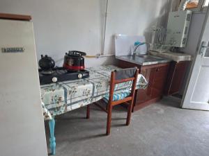 a kitchen with a table and a stove and a chair at myGrandma's home in Sheki