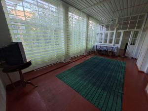 a room with a large window with a television and a rug at myGrandma's home in Sheki