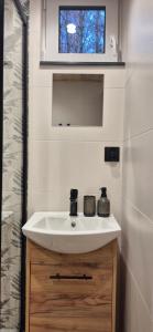 a bathroom with a white sink and a mirror at Odskocznia bliżej lasu in Korczyna