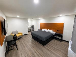 a bedroom with a bed and a chair and a television at Scenic Motel - El Monte in El Monte