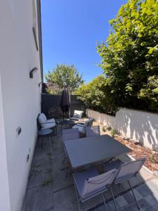 a patio with tables and chairs and an umbrella at Douce Escale, climatisé, 15 min de Strasbourg in Strasbourg