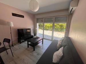 a living room with a couch and a tv and a table at Douce Escale, climatisé, 15 min de Strasbourg in Strasbourg