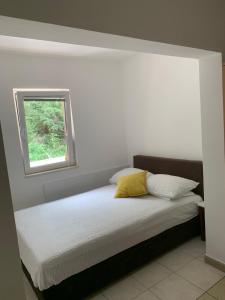 a bed with a yellow pillow and a window at Čanj apartmani in Čanj