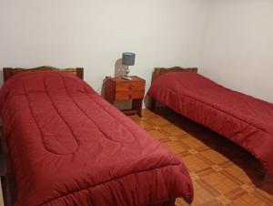 two beds with red covers in a room at Casa VYB in Malargüe